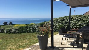 Un patio con vista sull'oceano, una pianta in vaso e mobili da esterno.