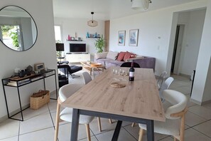Ein zeitgemäßer Wohnbereich mit Esstisch, Stühlen, einer Couch, einem Fernseher und einem Spiegel.