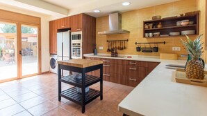 Een keuken met houten kasten, een magnetron, een fornuis en een spoelbak.