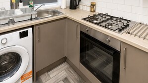 Une cuisine compacte équipée d’un lave-linge, d’une cuisinière et d’un four à micro-ondes.