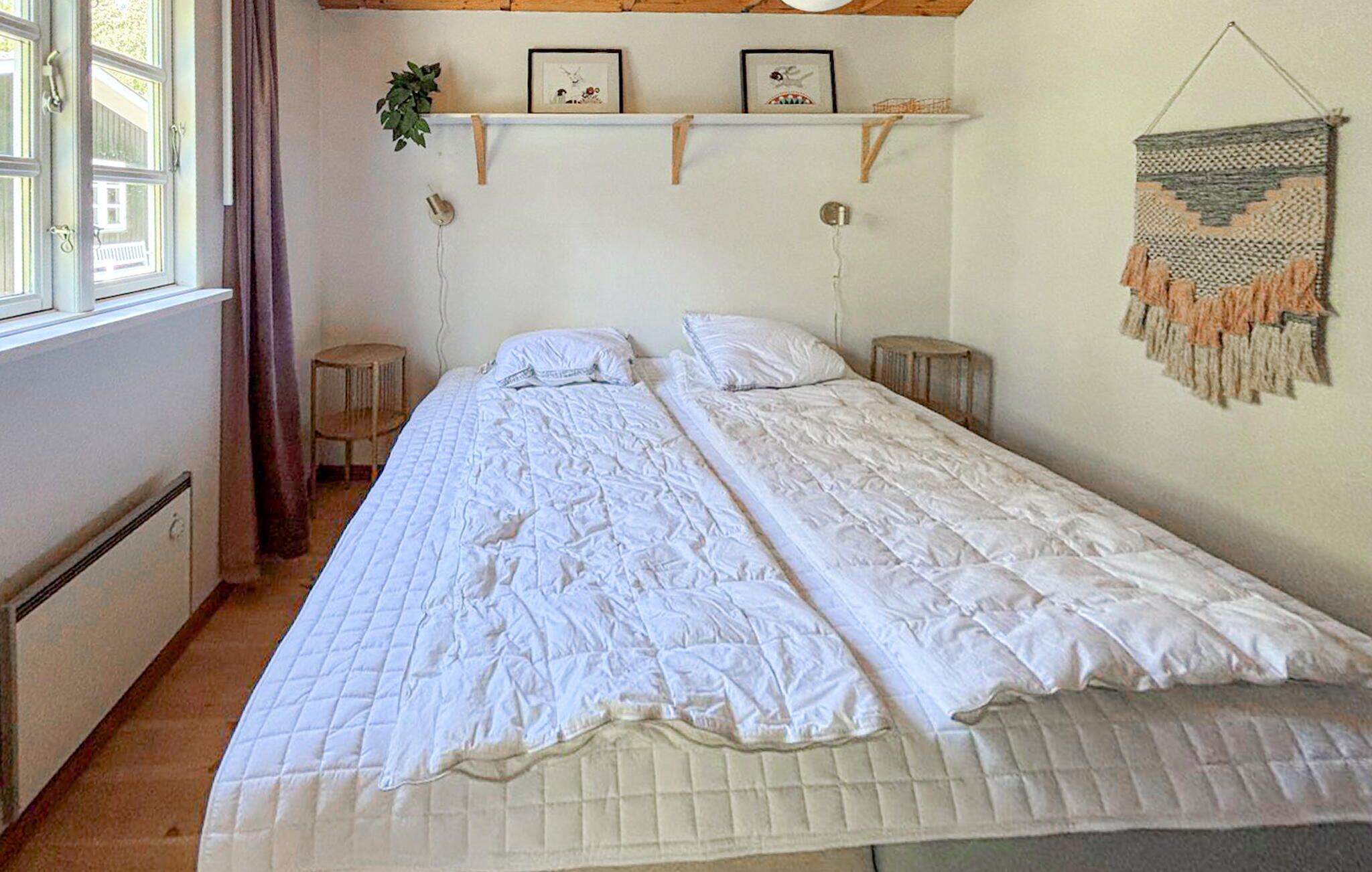 Une chambre avec deux lits, une fenêtre avec des rideaux, une étagère avec des photos encadrées et une décoration murale.