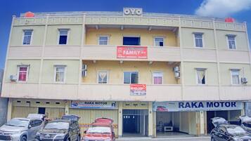 Un immeuble à plusieurs étages, sur lequel on peut lire l’enseigne « PENGINAPAN FAMILY Inn » et le nom du concessionnaire « RAKA MOTOR ».