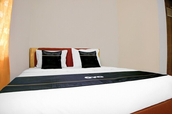 Una cama bien hecha con una colcha blanco y negro, dos almohadas y un cabecero.