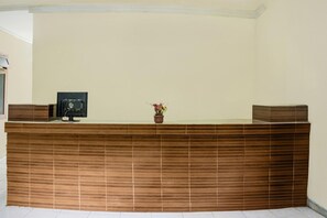 A reception desk with a wooden panel design, a framed photo, and a small potted plant.