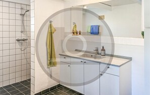 A modern bathroom with a shower, a sink with a mirror, and a towel rack. - 2 bedroom nice apartment in Skanderborg (Skanderborg)