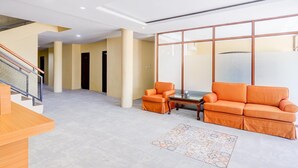 En rummelig lobby med trappe, sofa, sofabord og et mønstret tæppe.