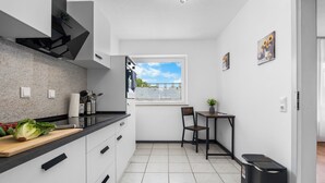 A modern kitchen with white cabinets, a black countertop, and a window with a view of the sky. - CASATUA Sun Design - Quiet - Workspace - Balcony - Trade Show - WiFi (Wuppertal)