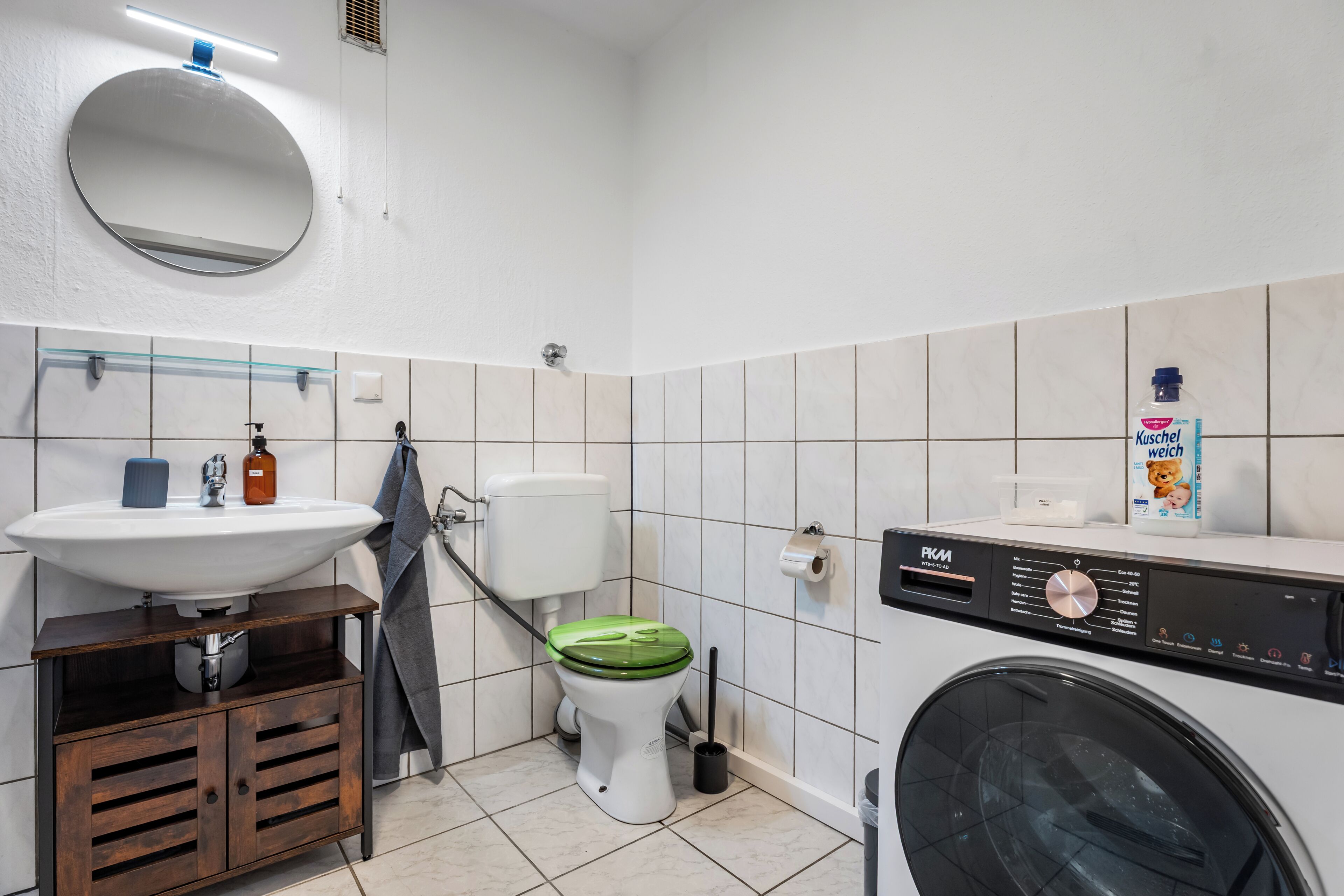 Ein kleines Badezimmer mit Waschbecken, Toilette und Waschmaschine.