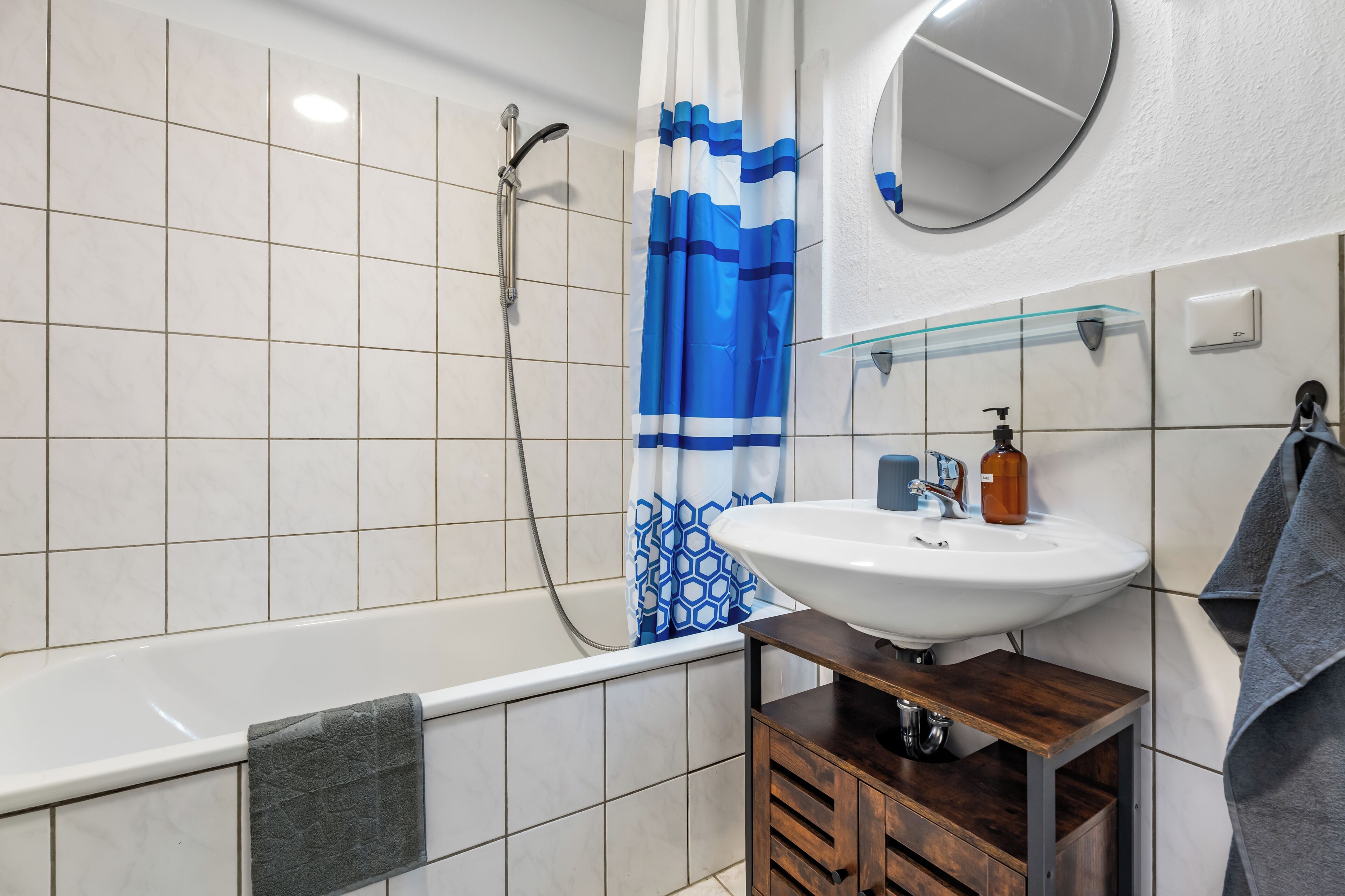 A bathroom with a bathtub, a shower, a sink, and a mirror.