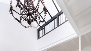 A spacious indoor area with a glass floor, potted plants, a decorative metal chandelier, and a staircase leading to an upper level. - Stylish House With Terrace. Casa del Buen Viaje (Seville)