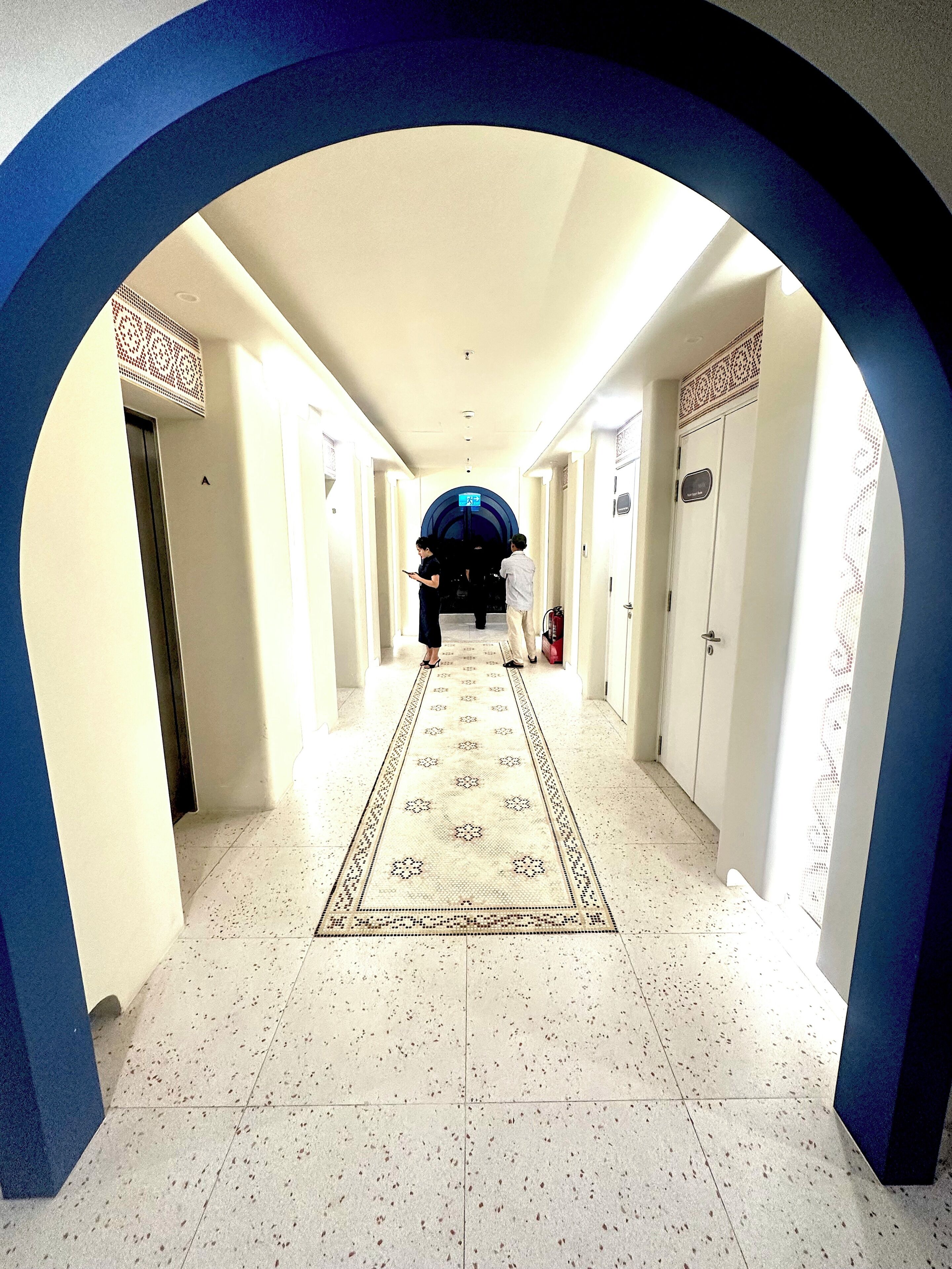 A hallway with a patterned carpet, white walls, and a blue archway.