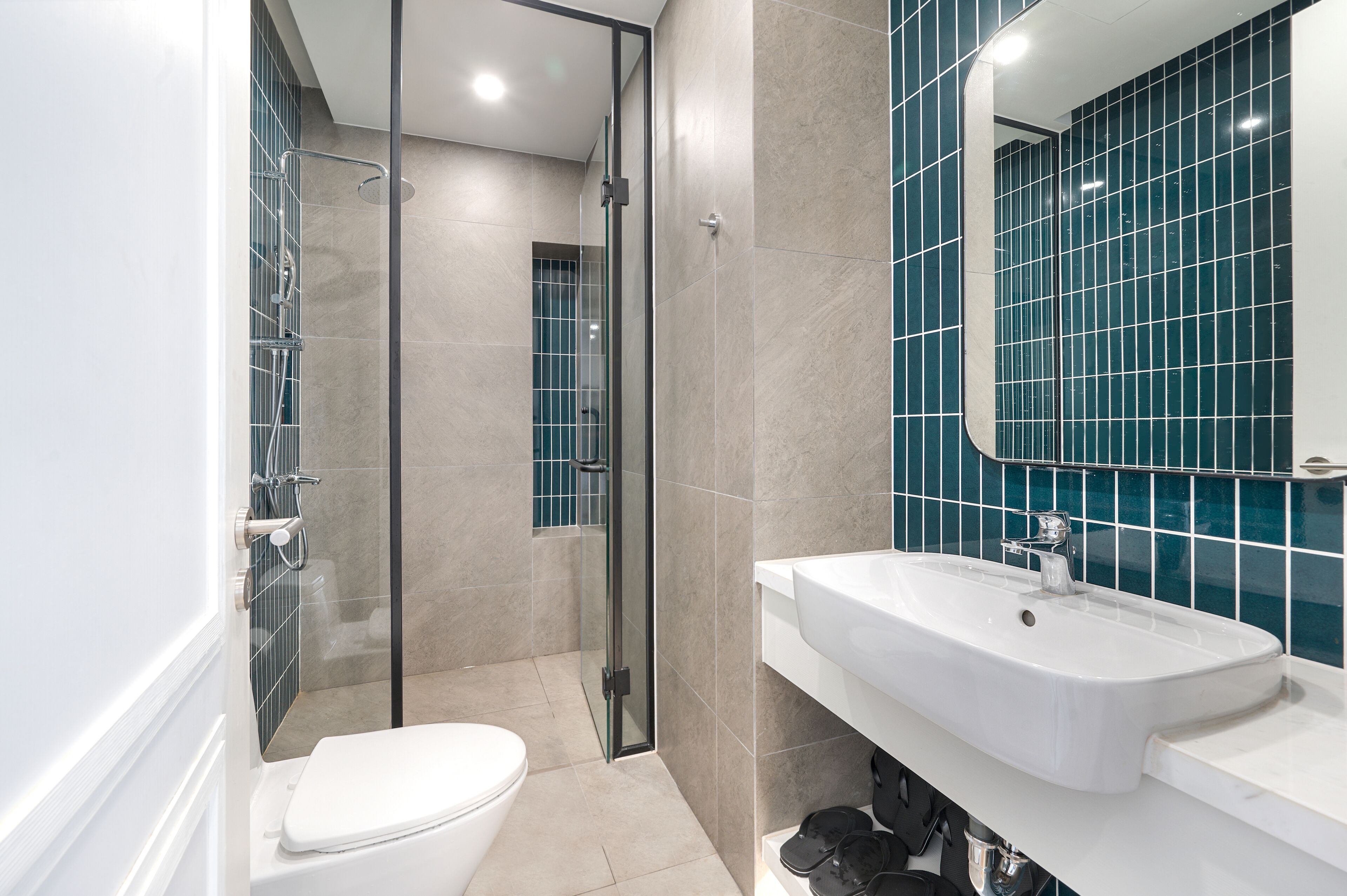 A modern bathroom with a glass-enclosed shower, a white sink, and a large mirror.