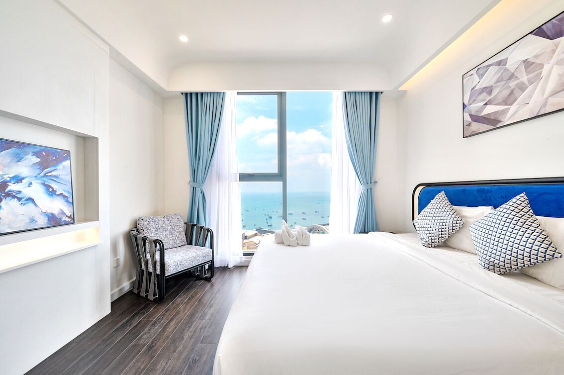 Une chambre d’hôtel avec un grand lit, une chaise, un tableau et une vue sur la mer.