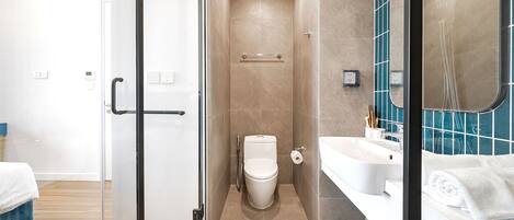 A modern bathroom with a glass shower enclosure, a toilet, a sink, and a mirror.