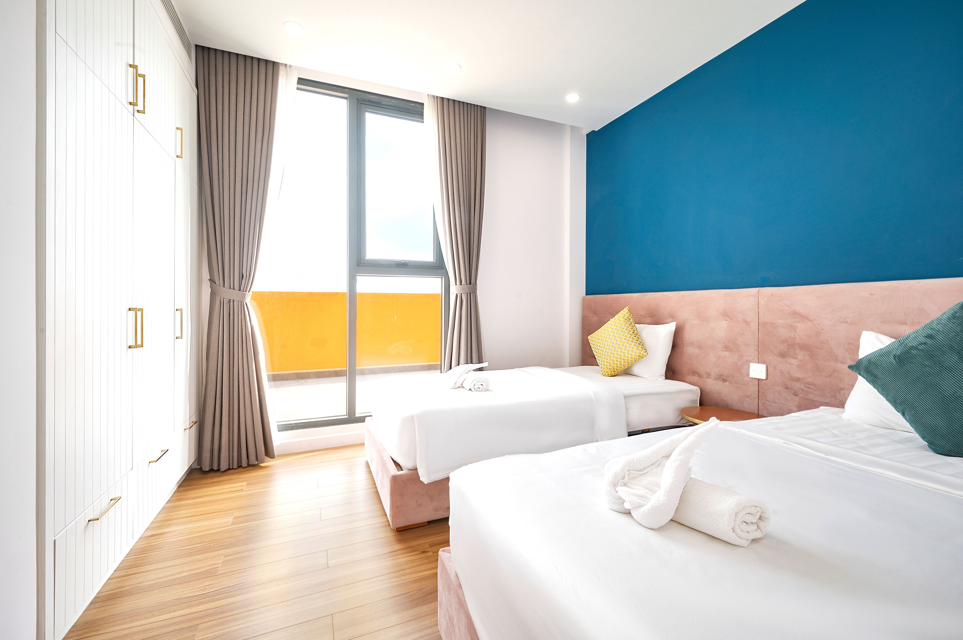Habitación de hotel con dos camas, un ventanal grande y vistas al exterior.