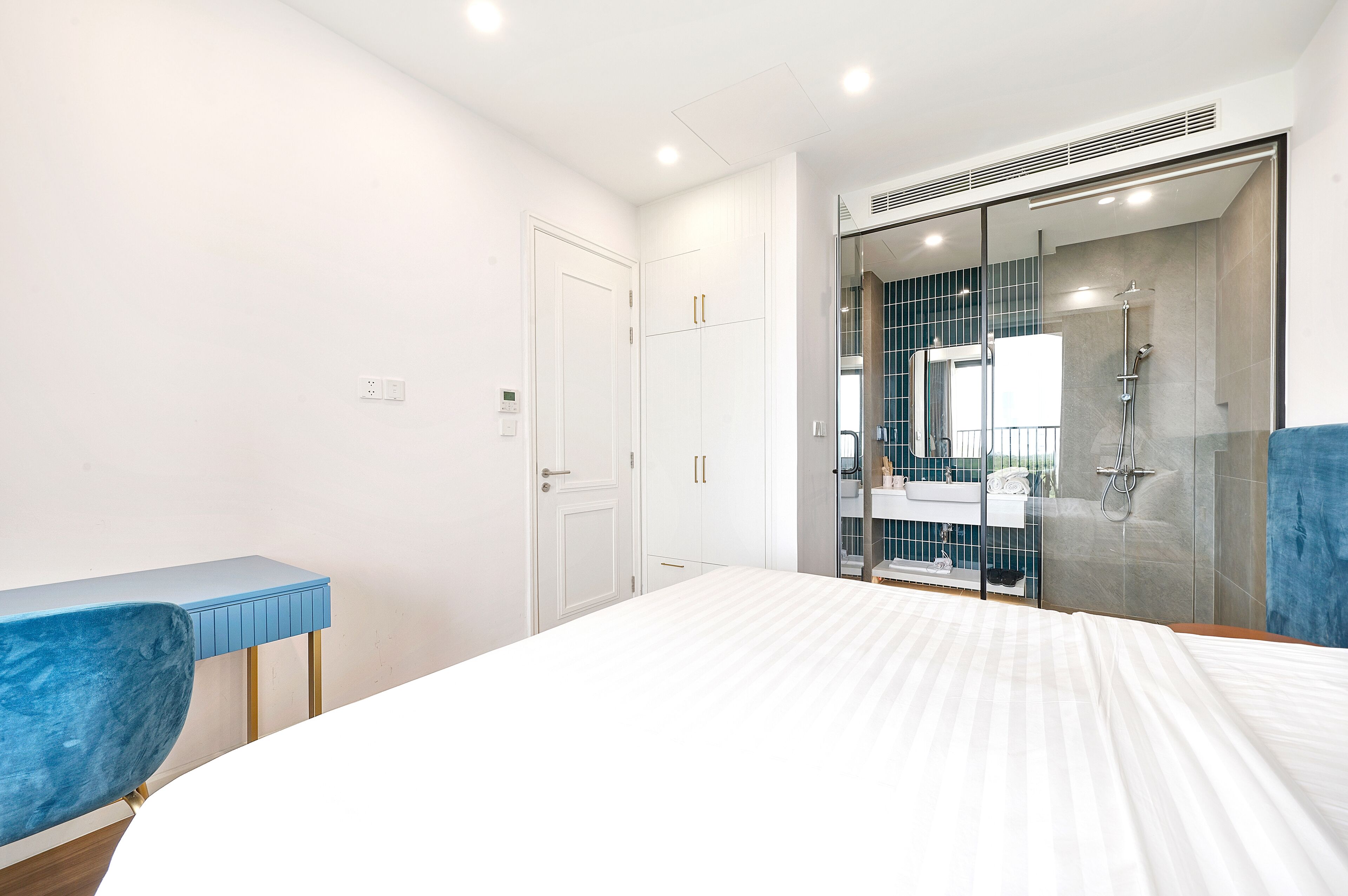 Une chambre à coucher comprenant un lit, un bureau, une chaise, une armoire et une salle de bain avec douche.