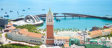 A coastal cityscape with a prominent clock tower, a bridge, and a marina with boats.