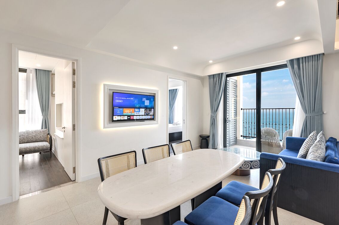Ein modernes Wohnzimmer mit Essbereich, einem Wand-Fernseher und einem Balkon mit Blick.