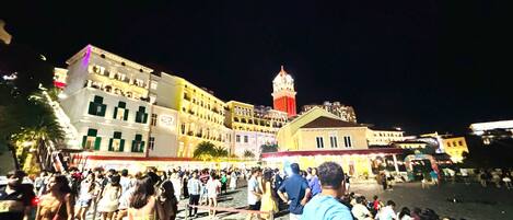 A crowded square with historic buildings and a prominent tower.