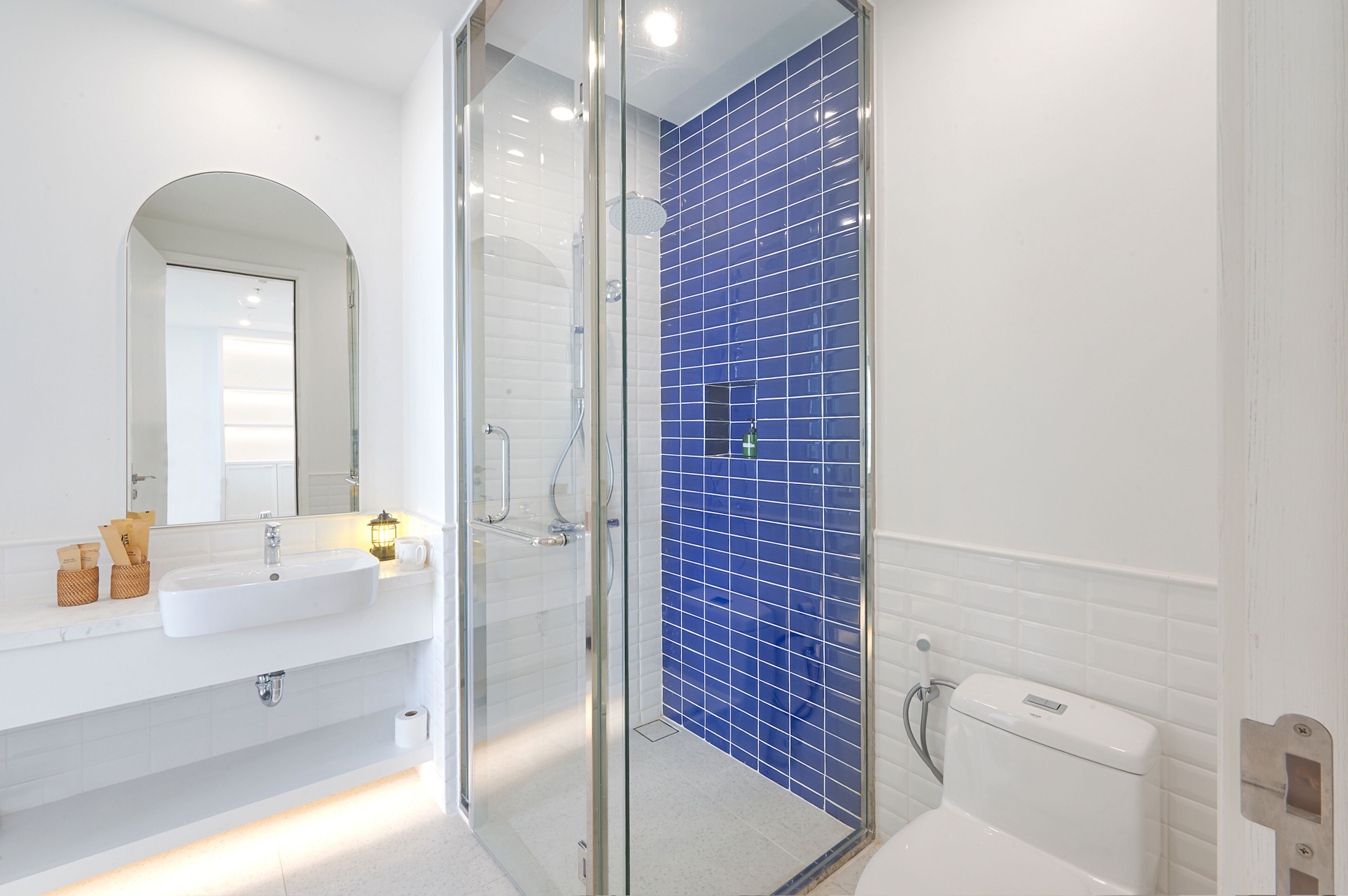 A modern bathroom with a glass-enclosed shower, white sink, and blue-tiled walls.