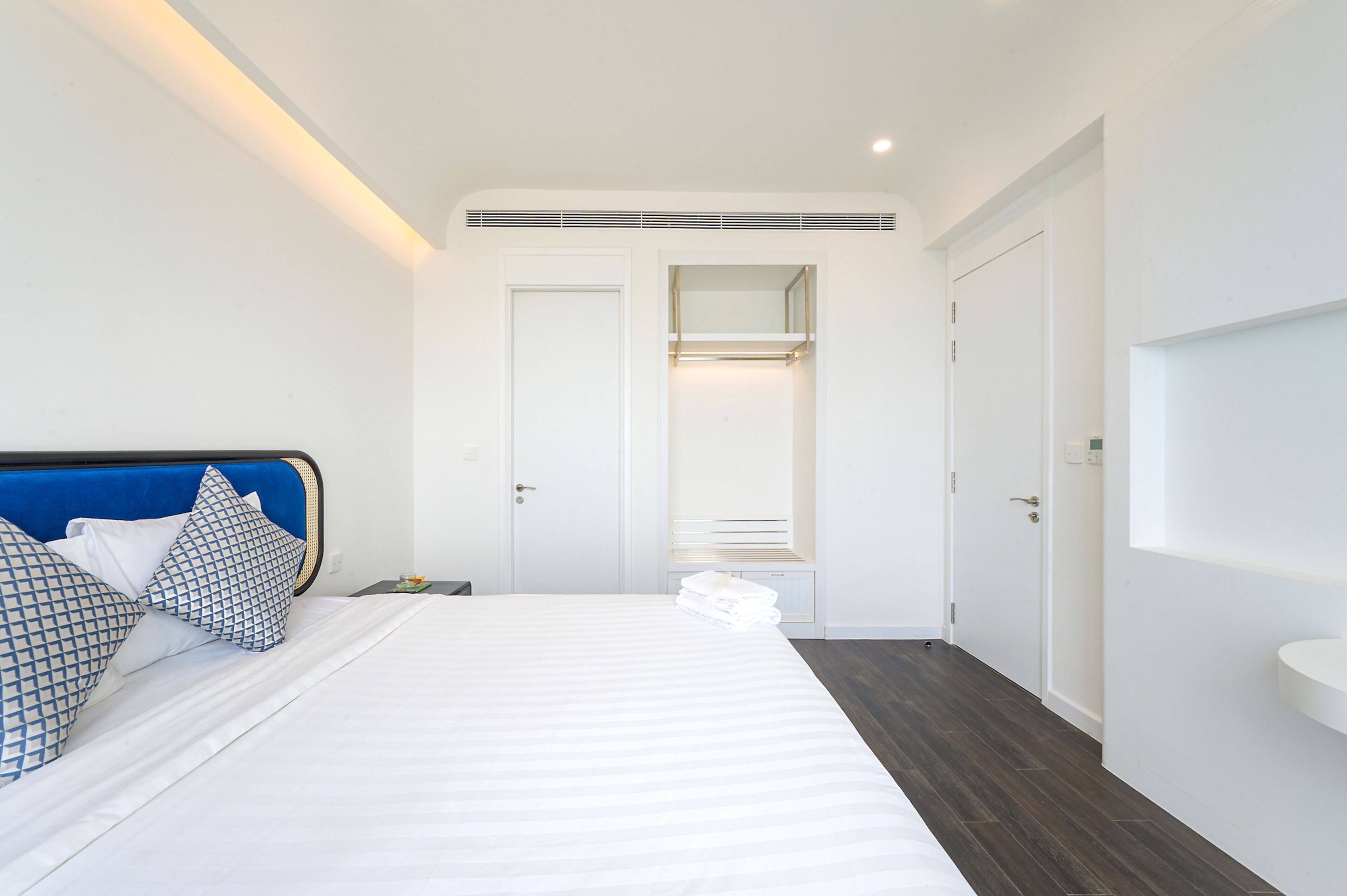 A bedroom with a bed, a nightstand, a wardrobe, and a bathroom with a sink.