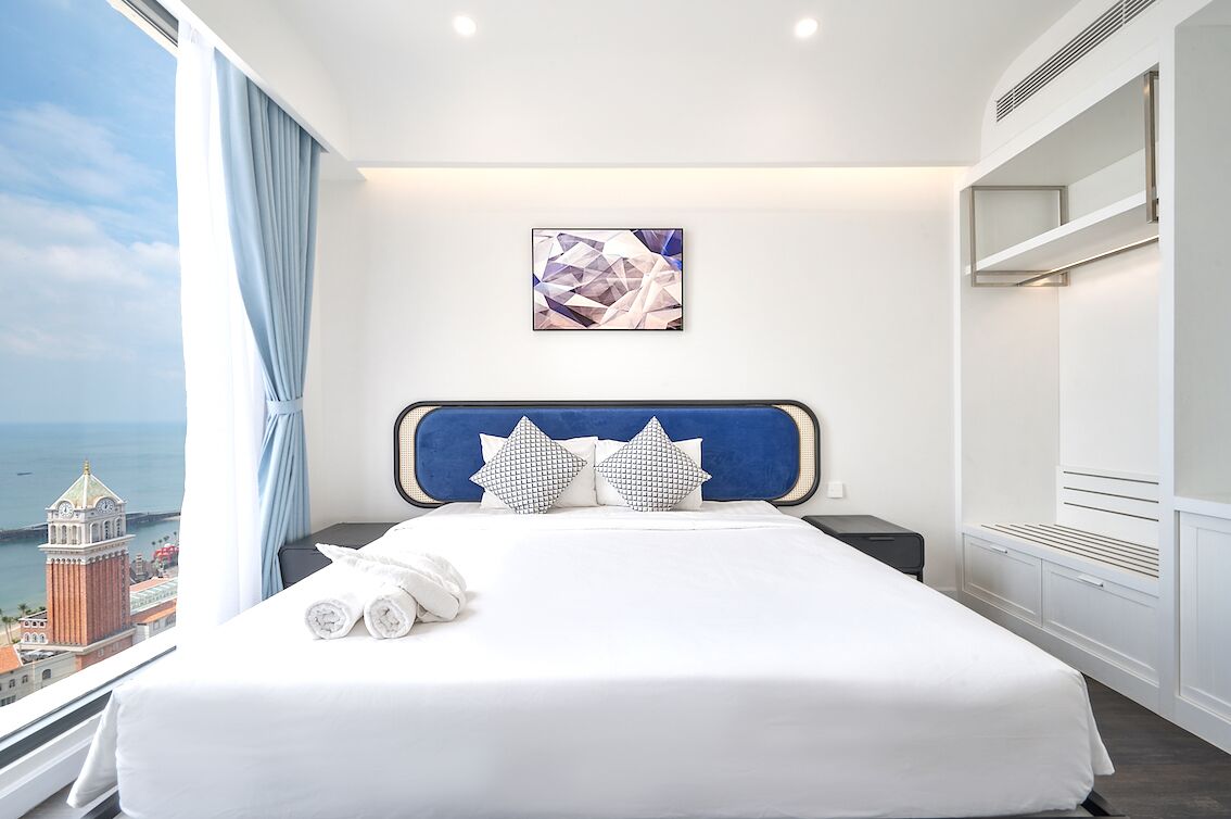 Une chambre d’hôtel avec un grand lit, une vue sur la ville et une tête de lit moderne.