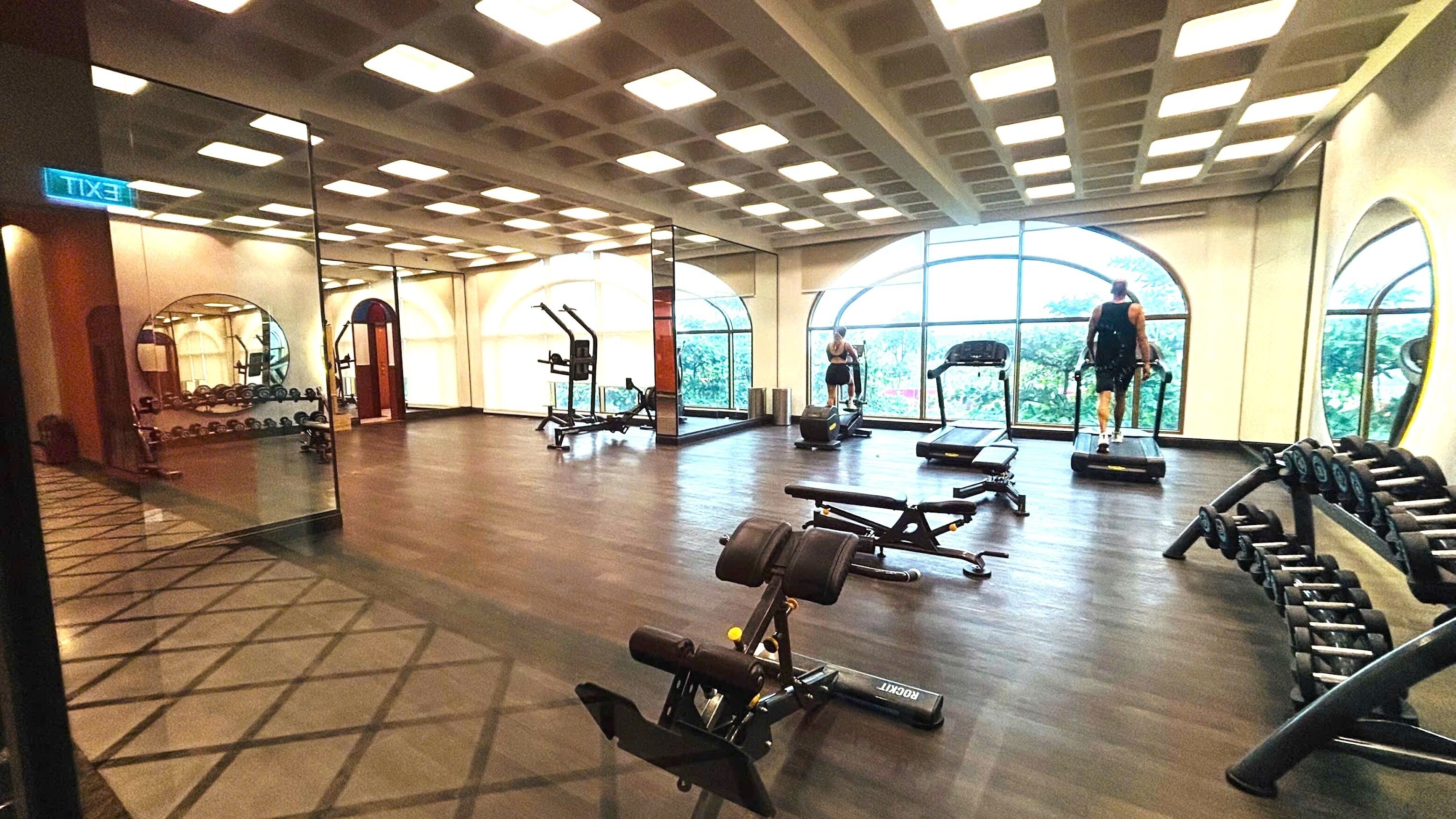 A gym with treadmills, weight machines, and dumbbells.