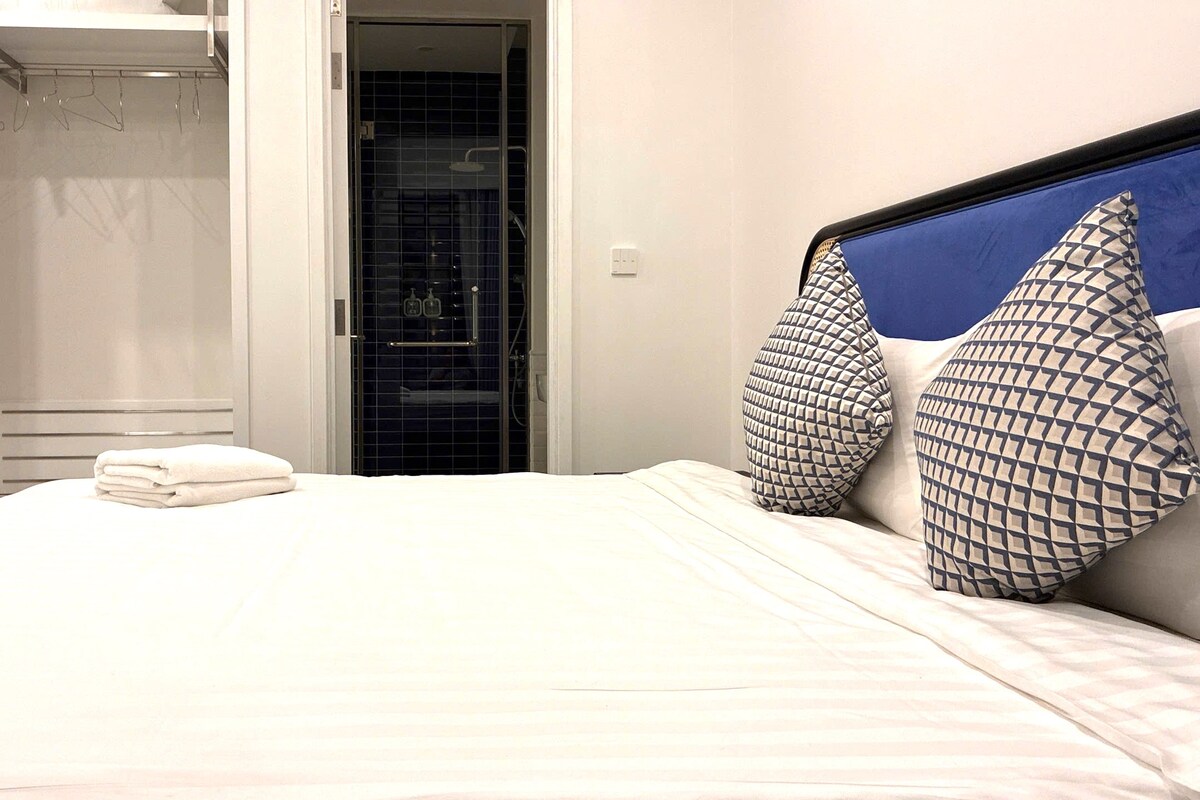 Habitación de hotel con cama, baño con ducha y puerta que da a un armario.
