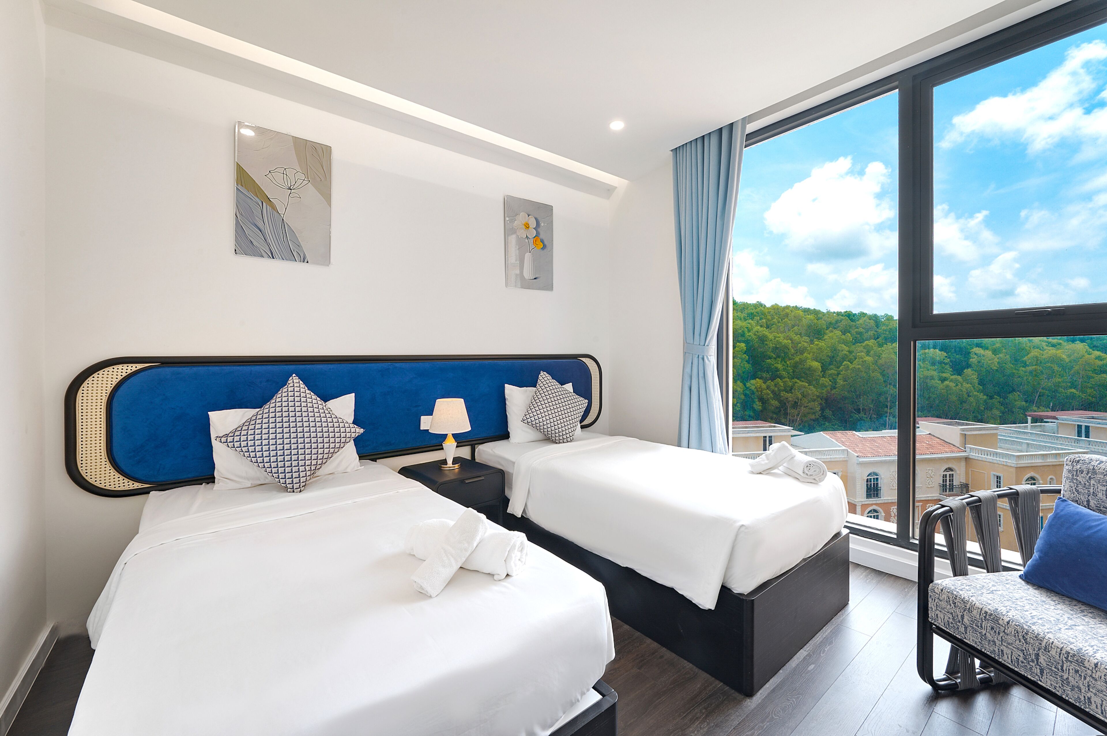 A hotel room with two beds, a view of the city, and artwork on the walls.