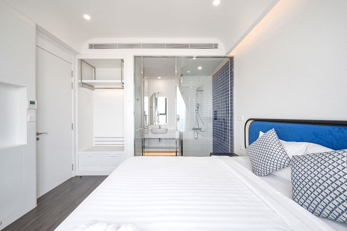 A modern bedroom with a large bed, a walk-in closet, and a bathroom with a shower.