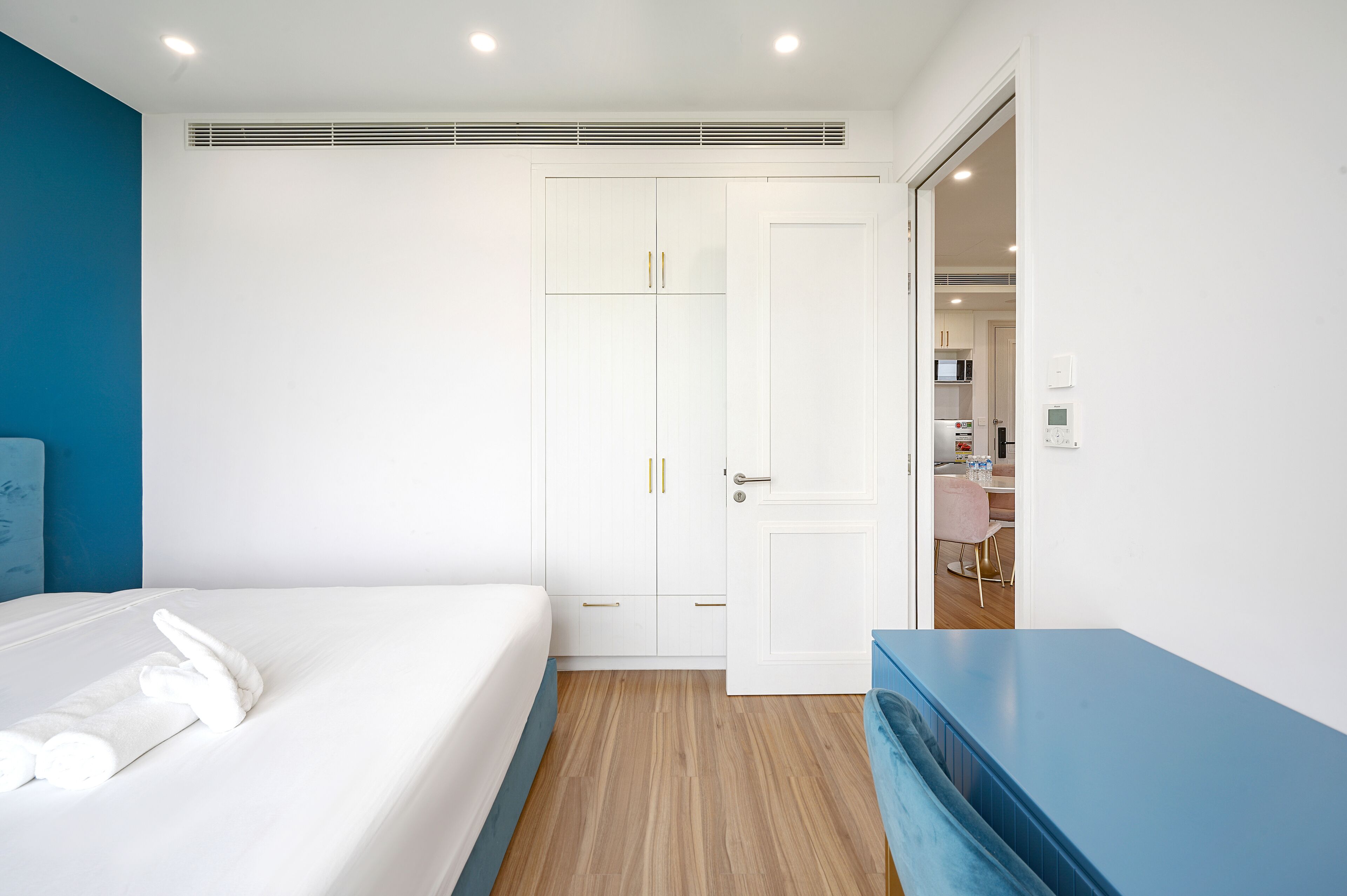 A bedroom with a bed, a wardrobe, a desk, and a bathroom visible through an open door.