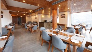 Un restaurante con techos de madera, mesas con sillas azules y vistas de la ciudad.