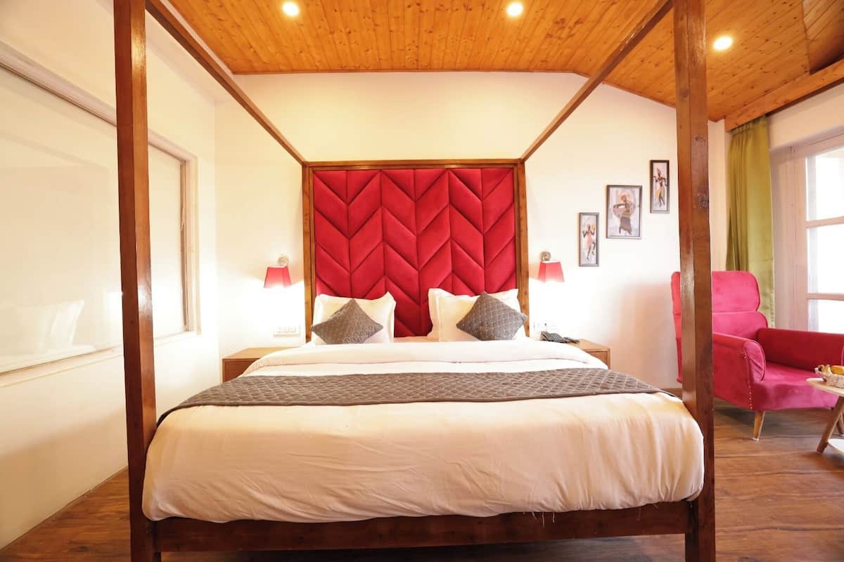 Un dormitorio con una cama grande, cabecera roja, dos lámparas de noche, una silla roja y una ventana.