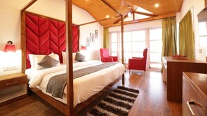 Una cama con dosel y dos columnas, con cabecera roja, techo de madera y un amplio ventanal con cortinas.
