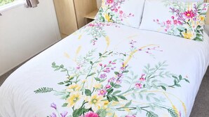 Un dormitorio con una cama, armario de madera y estante con plantas.