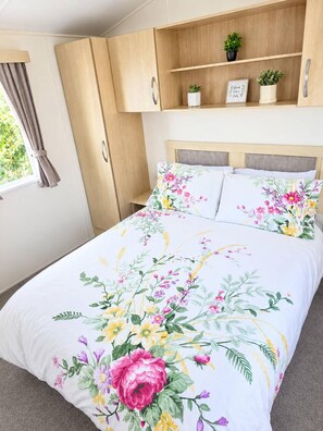 Quarto com cama, guarda-roupa de madeira e prateleira com plantas.