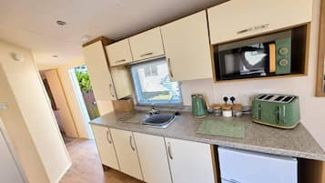 A compact kitchenette with a sink, a microwave, a toaster, and a small refrigerator.