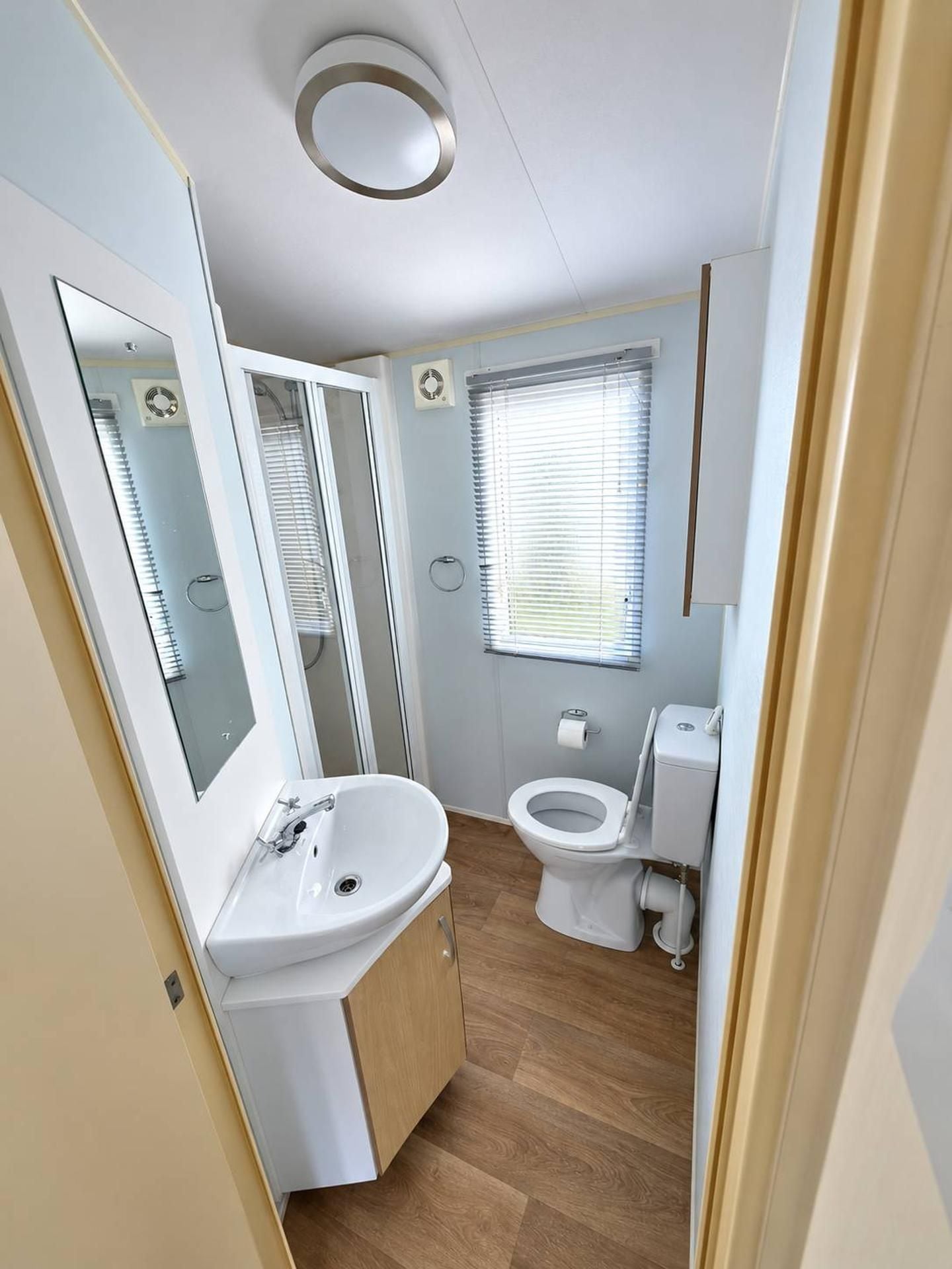 Ein kleines Badezimmer mit Waschbecken, Toilette und Fenster.