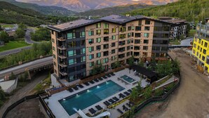 Un hôtel moderne à plusieurs étages, doté d’une piscine et offrant une vue sur les montagnes.