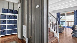 Ein geräumiger Wohnbereich mit Treppe, einem Stauraum mit blauen Behältern und Blick ins Freie.