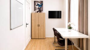 A modern conference room with a white table, black chairs, a wooden cabinet, a flat-screen TV, and a framed artwork on the wall. - Charming House with Garden Access (Wien)