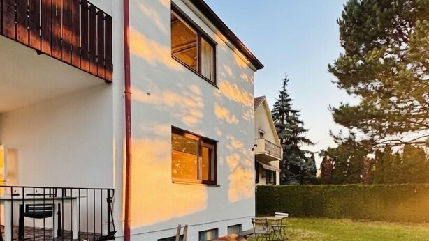 A two-story house with a balcony, a barbecue grill, and a well-maintained lawn. - Charming House with Garden Access (Wien)