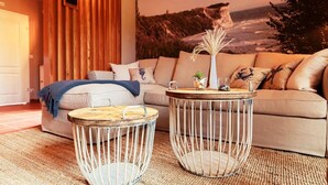Un salon avec un canapé, deux tables rondes et une fresque murale.