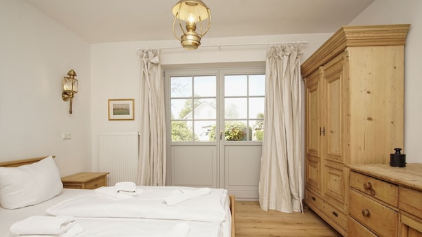 A bedroom with a bed, a wooden wardrobe, a nightstand, a window with curtains, and a wall-mounted light fixture. - Surfer's Paradise Wiek - Lee Vacation Rental (Wiek)