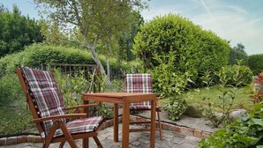 Two wooden chairs with plaid cushions and a small wooden table in a garden setting. - Surfer's Paradise Wiek - Lee Vacation Rental (Wiek)