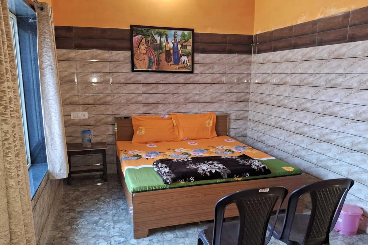 Ein Schlafzimmer mit Bett, Nachttisch, Sessel und einem Bild an der Wand.