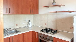A kitchen with wooden cabinets, a gas stove, a sink, and a countertop. - Cozy apartment in Kustici with WiFi (Kustici)