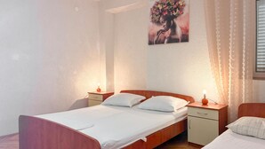 A double bed with a wooden frame, two bedside tables with lamps, a small cabinet, and a wall-mounted artwork. - Cozy apartment in Kustici with WiFi (Kustici)