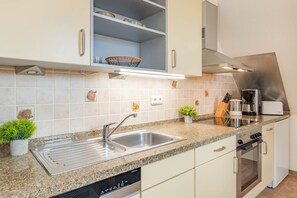 A modern kitchen with a stainless steel sink, a dishwasher, a built-in oven, and a coffee maker. - Vacation Rental 04 Fliederweg - located in an idyllic outskirt area with a balcony (Zinnowitz)