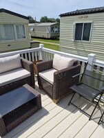 Una terraza con muebles de mimbre y una mesa de vidrio, rodeada de casas móviles.